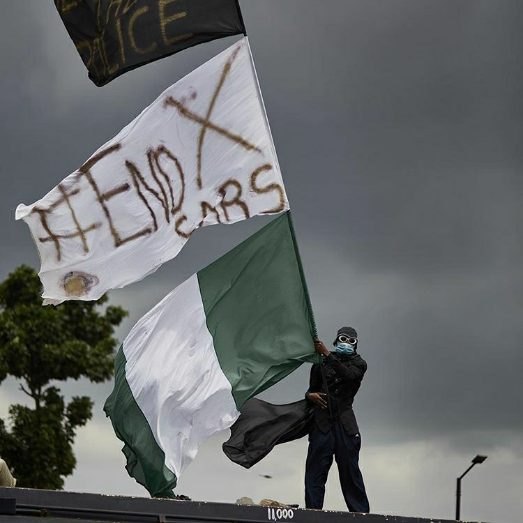 Nigerian man waving the Nigerian flag during the #EndSARS protest in Nigeria