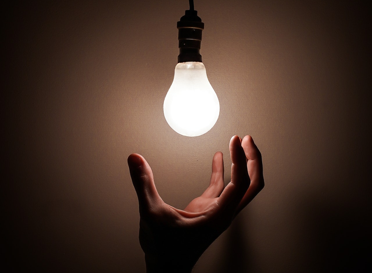 Man's hand underneath a light bulb - 5 ways to steal ideas like an artist