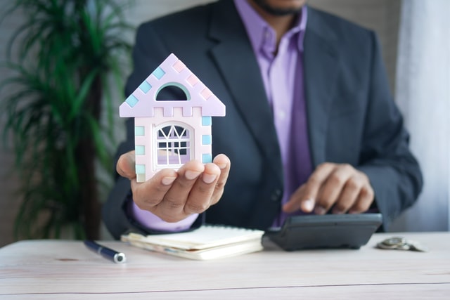 Black man holding a small house on his hand