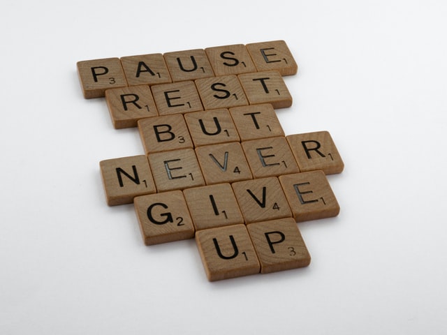 Scrabble tiles displaying the words: pause, rest but never give up