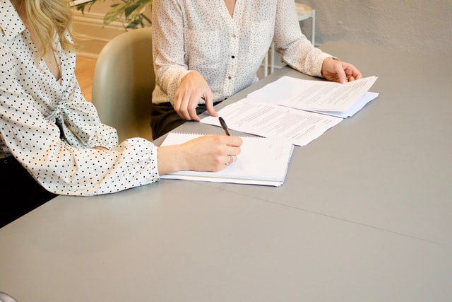 Two females signing documents on the table