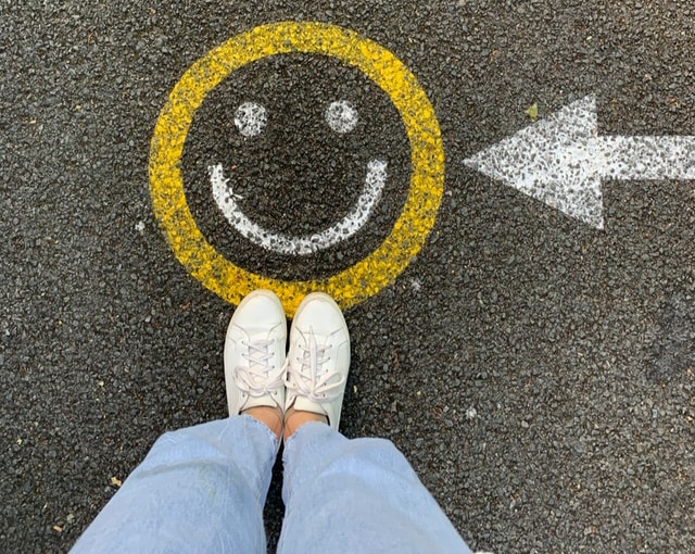 Girls' feet on a yellow happy emoji on the ground