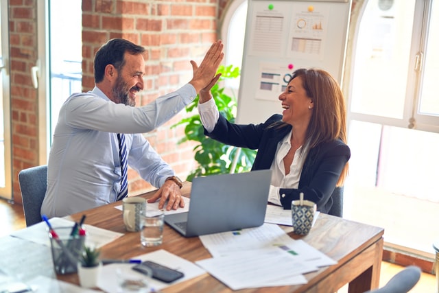 Two business man and woman giving high five