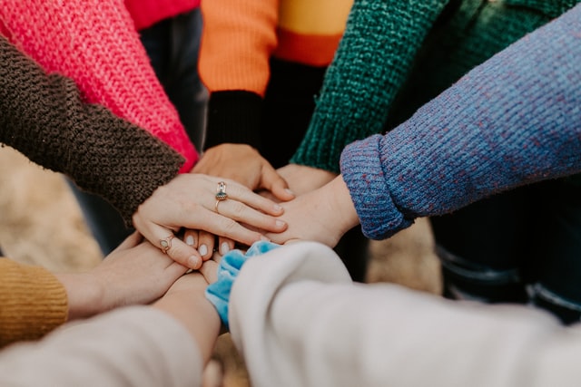 Groups of people putting their hands on top of each other