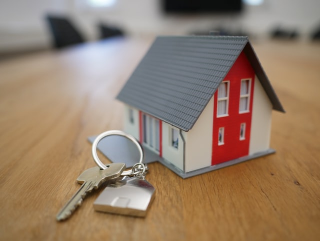 Miniature house and keys on a wooden surface