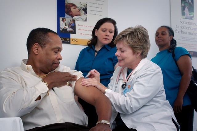 African-American man being injected with syringe by a medical doctor